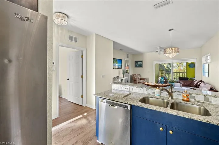 Kitchen with light stone countertops, sink, stainless steel dishwasher, and light hardwood / wood-style floors