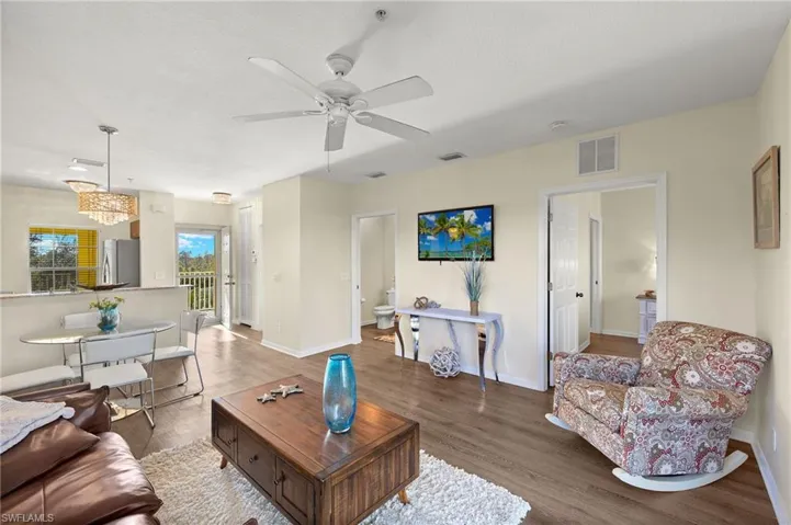 Living room featuring wood-type flooring and ceiling fan with notable chandelier
