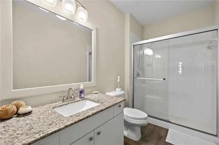 Bathroom with hardwood / wood-style floors, vanity, toilet, and walk in shower