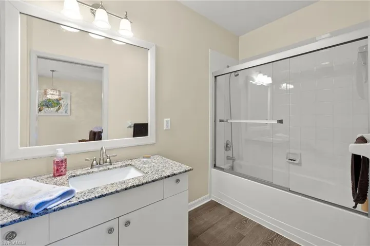 Bathroom featuring shower / bath combination with glass door, wood-type flooring, and vanity