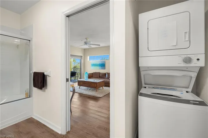 Laundry area featuring ceiling fan, stacked washing maching and dryer, and hardwood / wood-style flooring