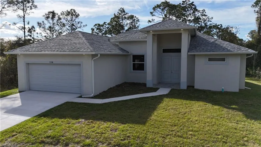 View of front of property featuring a garage and a front lawn