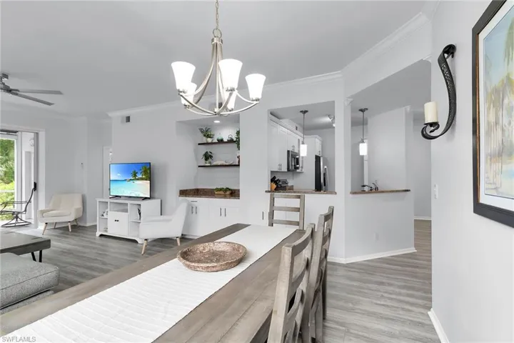 Dining space with crown molding, light wood-type flooring, a chandelier, and ceiling fan