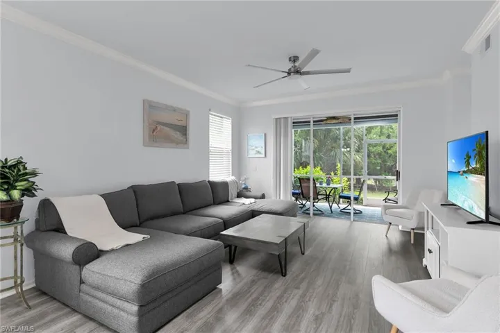 Living room with crown molding, light wood-type flooring, a ceiling fan, and a sunroom