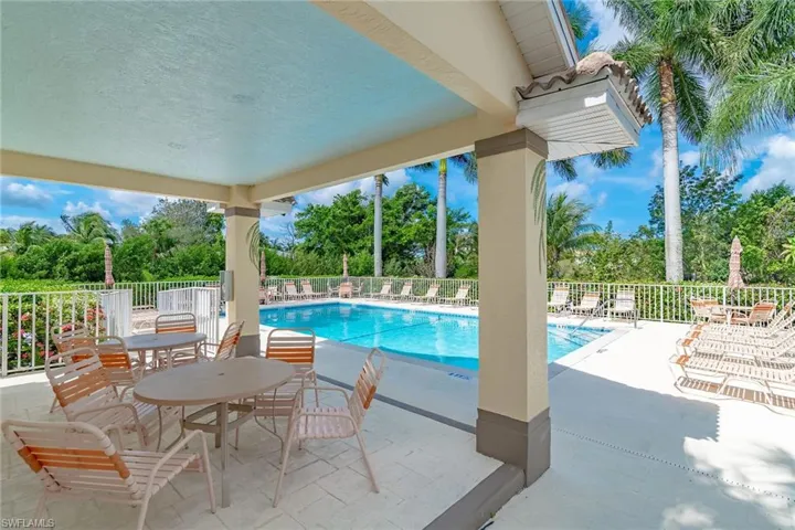 Community pool with a patio and view of wooded area