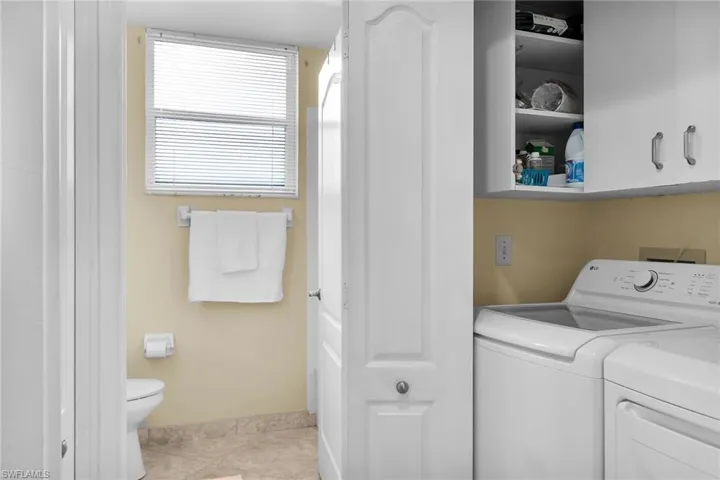 Laundry area featuring light tile patterned floors, separate washer and dryer, and cabinet space