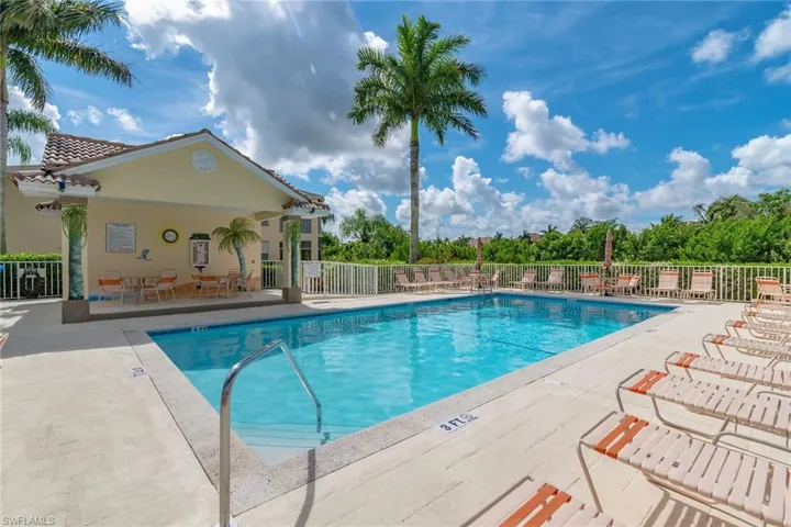 Community pool with a patio area and view of wooded area