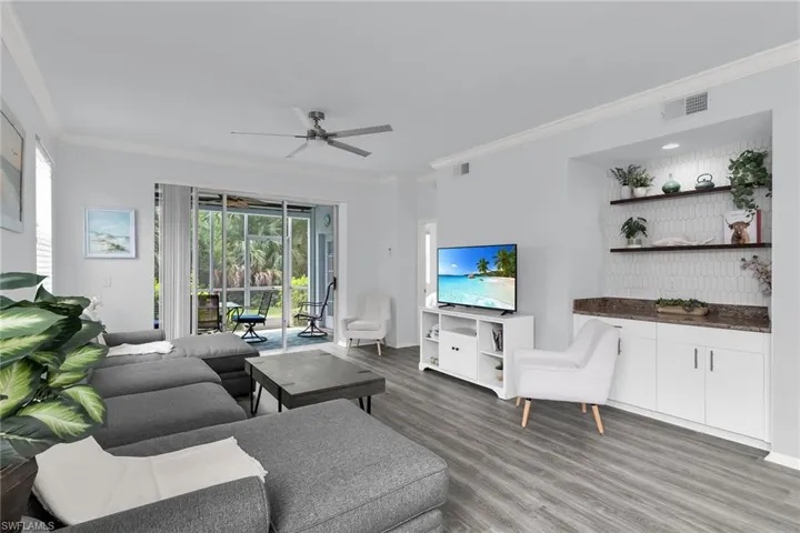 Living room featuring ornamental molding, light wood-style floors, and ceiling fan
