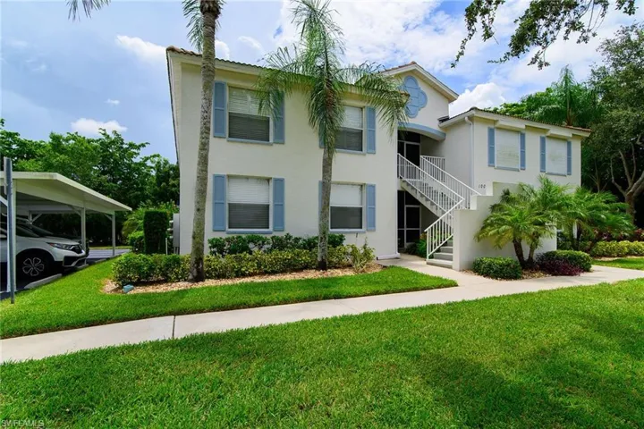 View of front of house featuring stucco siding, a front yard, and stairway