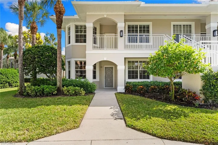 View of front of house featuring stucco siding, a balcony, and a front yard