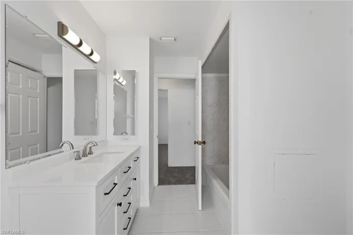 Bathroom featuring a dual vanity with white cabinetry, a light-toned countertop, and brushed nickel fixtures