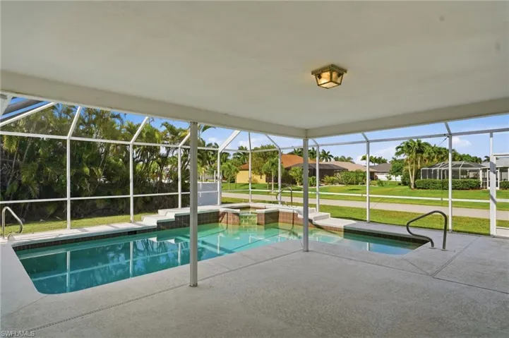 Screened lanai featuring a swimming pool and attached spa with tiered entry steps, integrated handrails, and a textured concrete deck