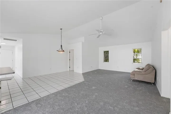 Spacious open-concept interior featuring light gray carpeting and white tile flooring