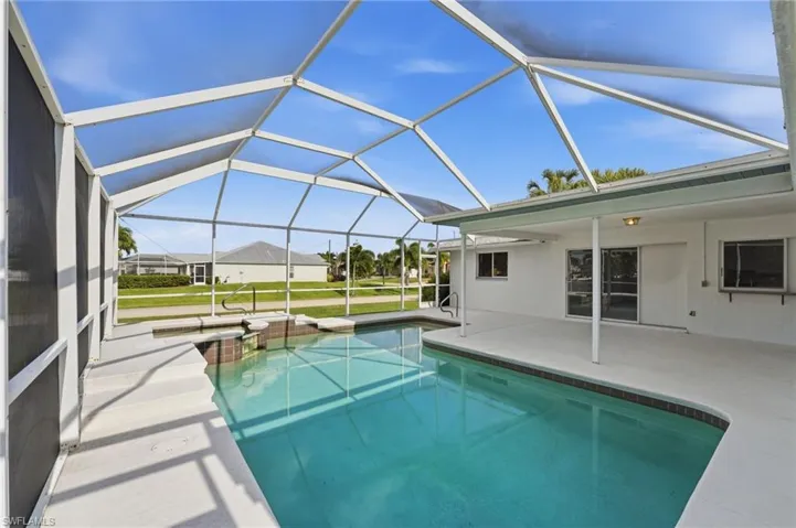 Screened lanai featuring a swimming pool, integrated spa, and expansive patio area
