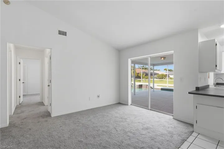 Bright interior space featuring light gray carpet, white walls, and a vaulted ceiling