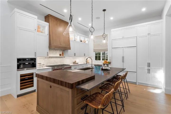 Kitchen with a sink, beverage cooler, a kitchen island with sink, decorative backsplash, and a breakfast bar area
