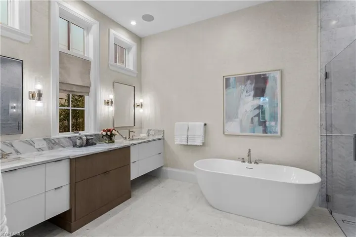 Full bathroom with a freestanding tub, double vanity, a stall shower, and baseboards