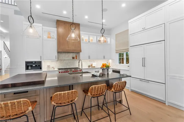 Kitchen featuring paneled fridge, a sink, tasteful backsplash, dark countertops, and recessed lighting