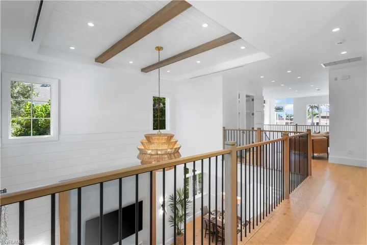 Corridor with light wood-style floors, recessed lighting, wooden ceiling with exposed beams, and an upstairs landing