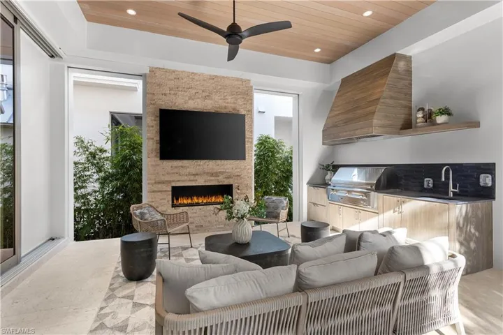 Living area featuring wooden ceiling, an outdoor stone fireplace, recessed lighting, and a ceiling fan
