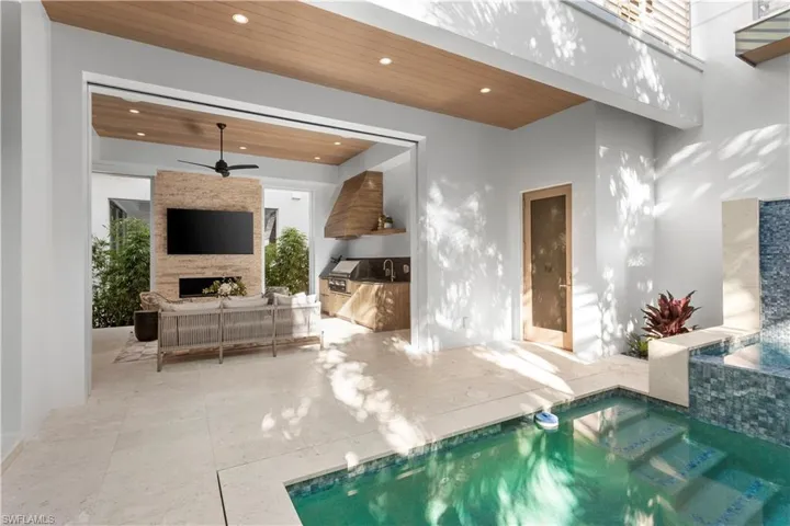 Indoor pool featuring ceiling fan, a sink, and a fireplace