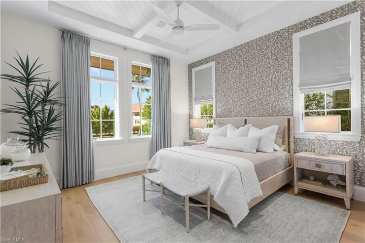 Bedroom featuring wallpapered walls, light wood-type flooring, coffered ceiling, baseboards, and beamed ceiling