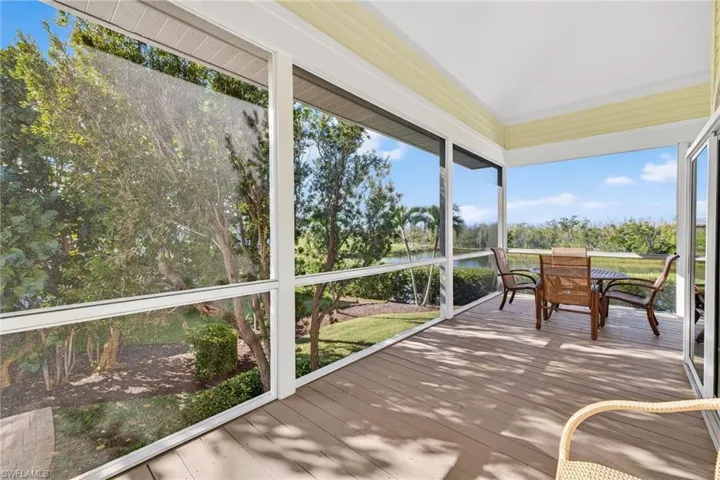 Sunroom / solarium with a water view, outdoor dining space, and hardwood / wood-style floors