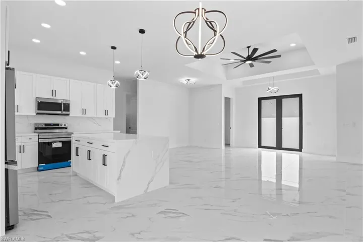 Kitchen with decorative light fixtures, white cabinetry, light marble finish floors, stainless steel appliances, and recessed lighting