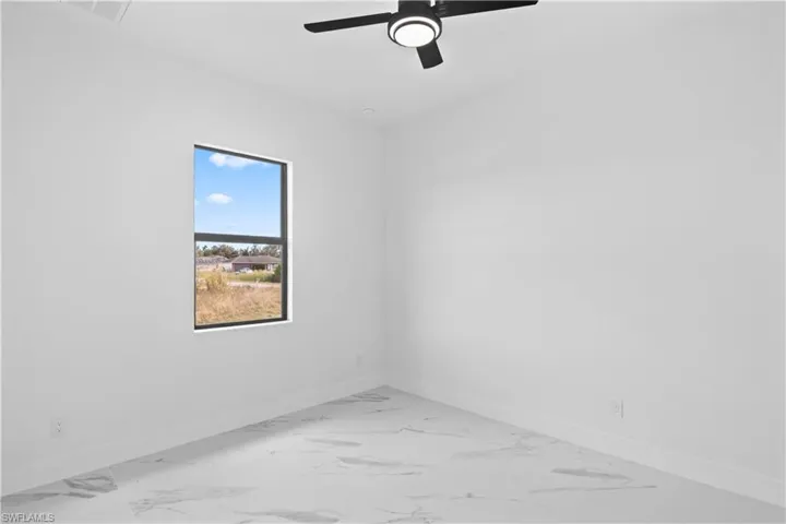 Spare room featuring light marble finish floors and ceiling fan