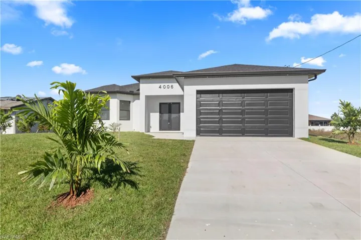 Prairie-style house featuring concrete driveway, stucco siding, an attached garage, and a front yard