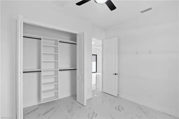 Unfurnished bedroom with light marble finish floors, a closet, and a ceiling fan