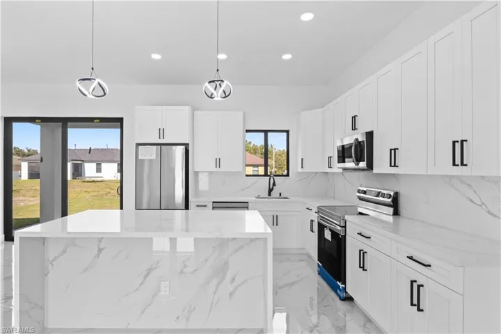 Kitchen featuring stainless steel appliances, recessed lighting, white cabinets, and decorative light fixtures