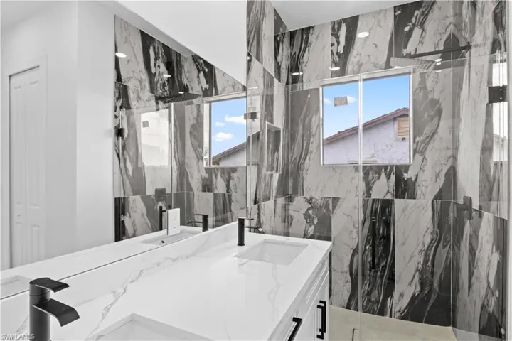 Bathroom featuring vanity, a marble finish shower, healthy amount of natural light, and a closet