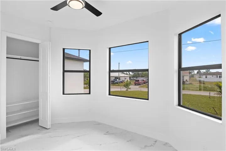 Unfurnished bedroom with light marble finish flooring, ceiling fan, and a closet