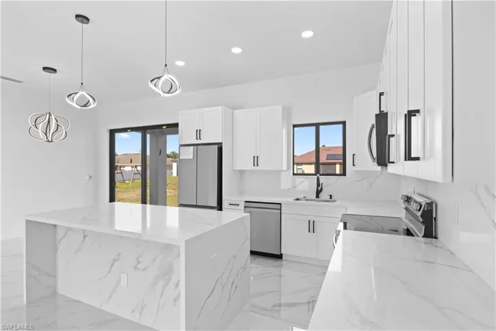 Kitchen with white cabinetry, decorative light fixtures, light stone counters, recessed lighting, and appliances with stainless steel finishes