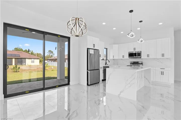 Kitchen featuring white cabinets, pendant lighting, stainless steel appliances, a chandelier, and recessed lighting