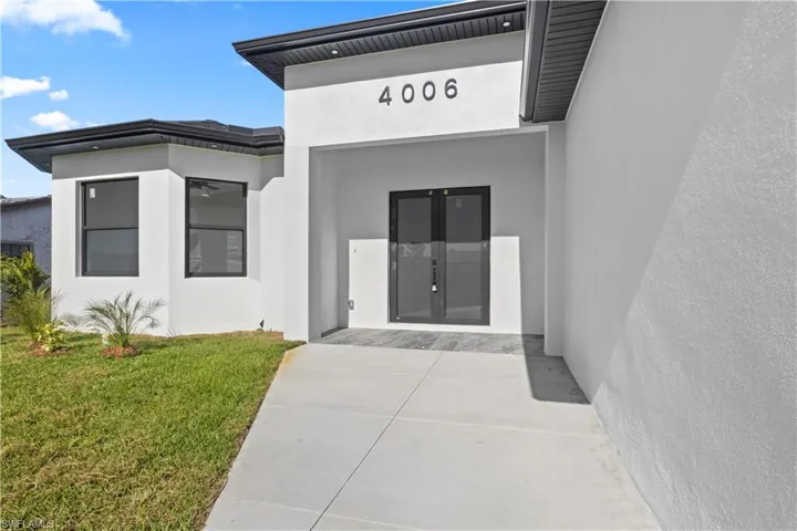 Entrance to property with a yard, stucco siding, and french doors