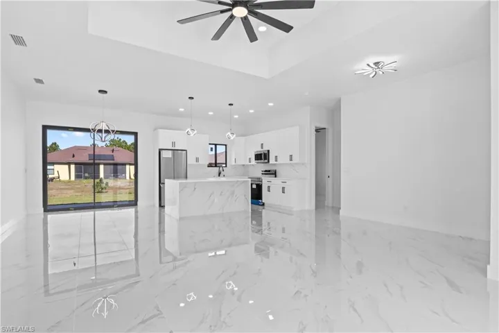 Unfurnished living room featuring light marble finish floors, a raised ceiling, recessed lighting, and ceiling fan