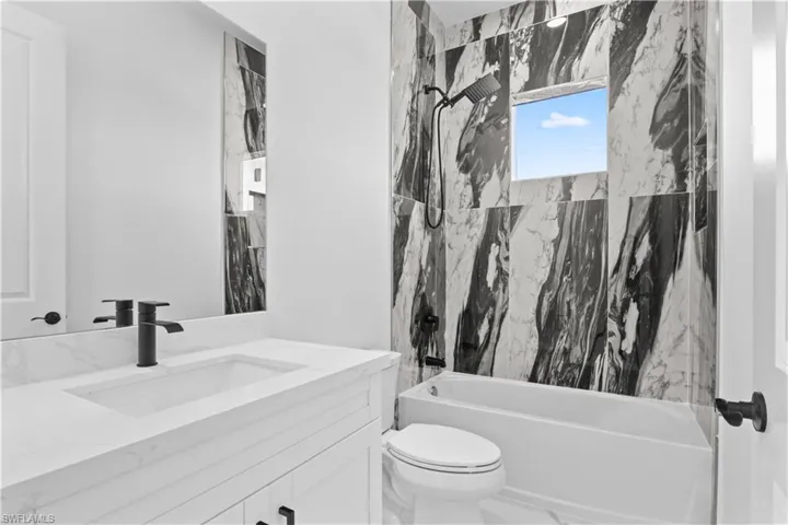 Full bath with a combined bath / shower with marble appearance, vanity, and marble tiled floors