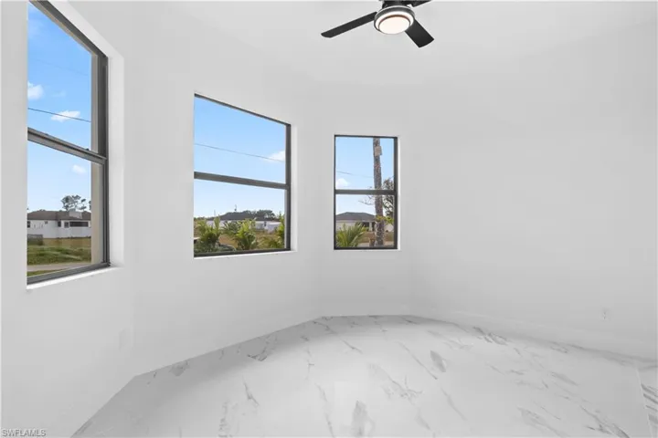 Empty room featuring light marble finish flooring and a ceiling fan