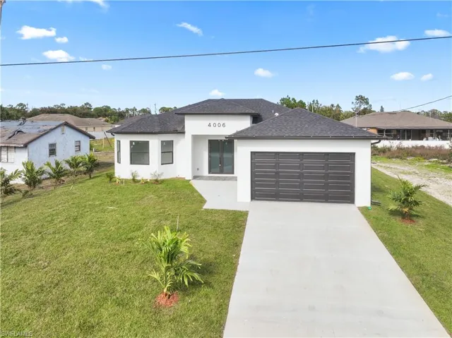 View of front of property with concrete driveway, stucco siding, a front yard, a shingled roof, and an attached garage
