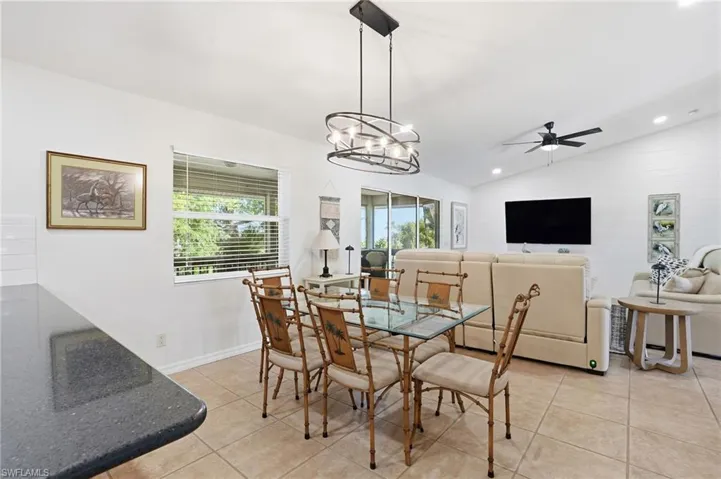 Dining space with a chandelier, light tile patterned floors, lofted ceiling, ceiling fan, and recessed lighting