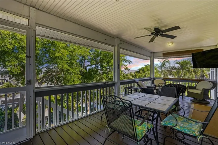 Wooden deck with a ceiling fan, outdoor dining space, and a sunroom