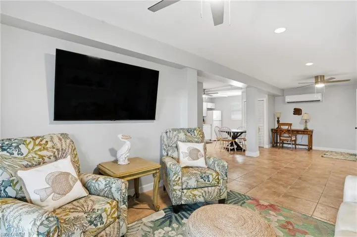 Tiled living room featuring ceiling fan, recessed lighting, and a wall unit AC