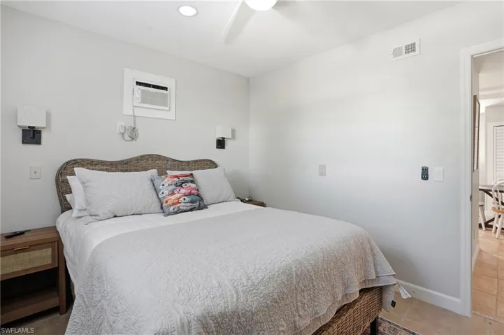 Bedroom featuring a ceiling fan, tile patterned floors, and an AC wall unit