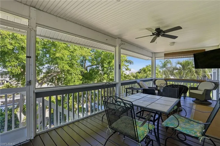 Wooden terrace with ceiling fan, a sunroom, and outdoor dining area