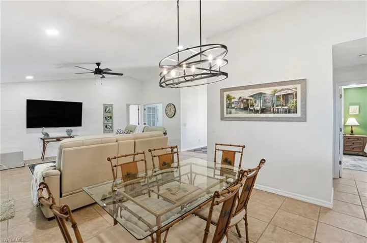 Dining area featuring vaulted ceiling, light tile patterned floors, a chandelier, a ceiling fan, and recessed lighting