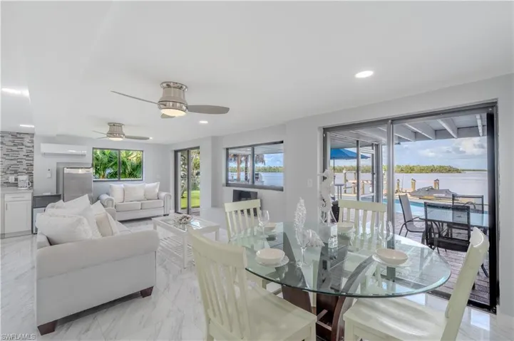 Dining room with light tile finish flooring, a water view, recessed lighting, a ceiling fan, and a wall unit AC - Virtually Edited Image