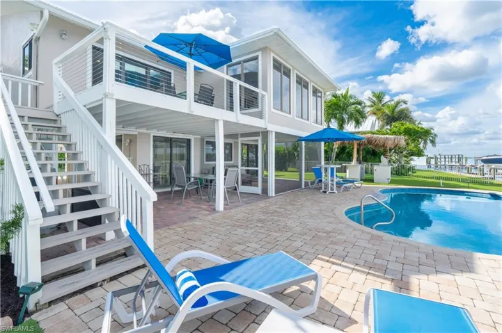 View of swimming pool with stairway, a patio area, outdoor dining space, and a sunroom - Virtually Edited Image