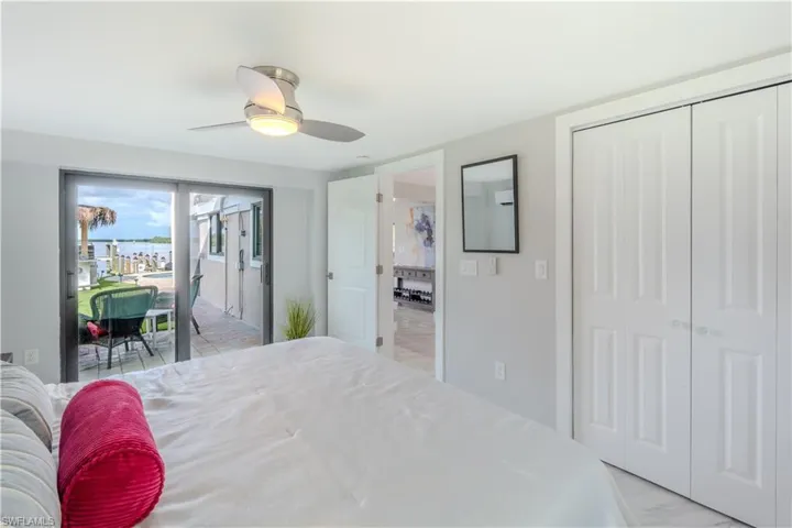Bedroom featuring a ceiling fan, light marble tile finish flooring, access to exterior, and a closet - Virtually Edited Image